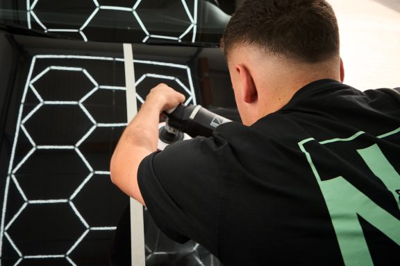 Person arbeitet an einer Oberfläche mit einem Werkzeug und einer hexagonalen Musterung.